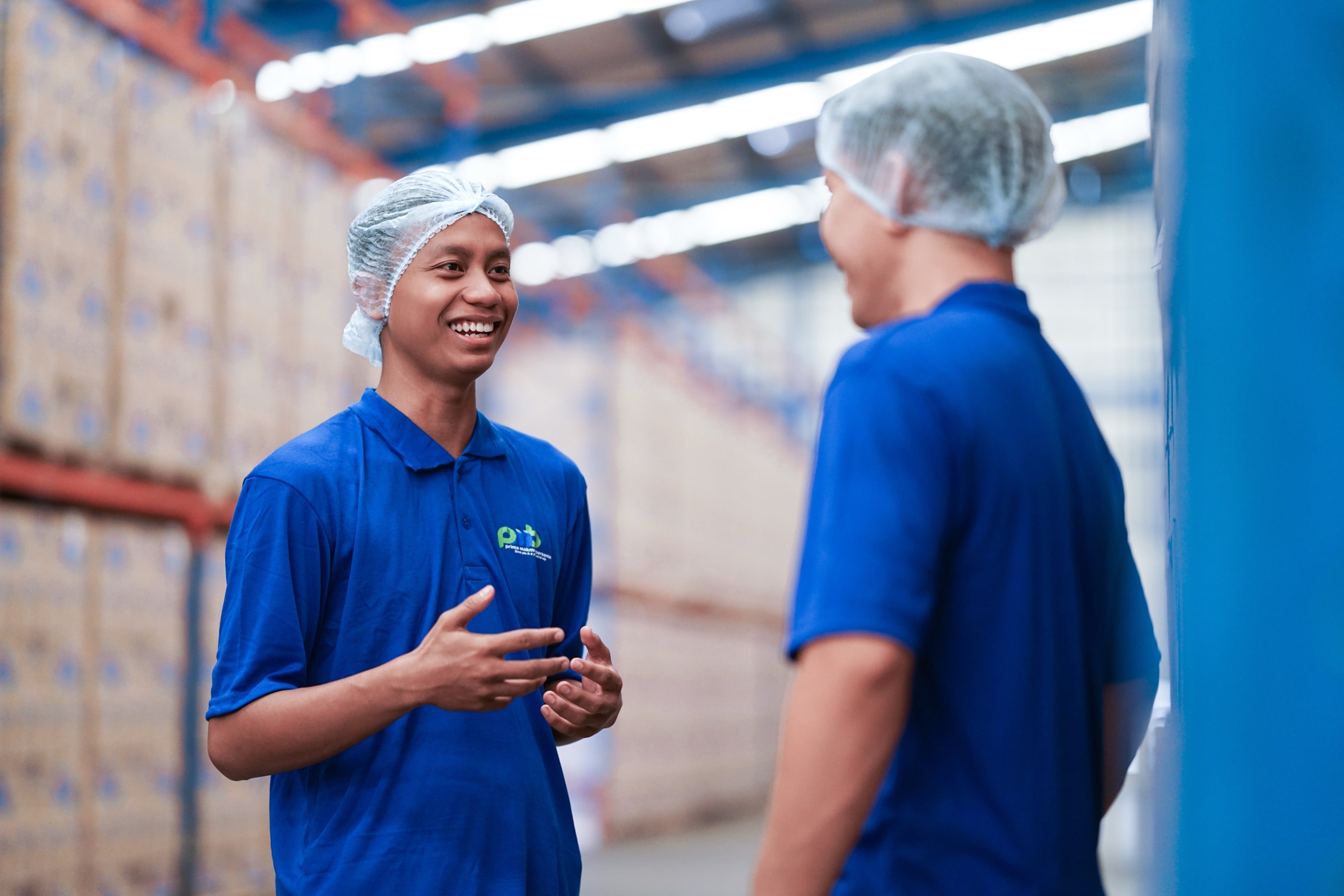 Two PMB workers talking in a warehouse aisle
